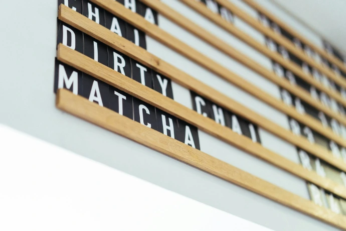 A wooden letter board displaying coffee shop menu items.